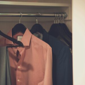Stylish men's wardrobe featuring a formal suit and pink dress shirt neatly hung on hangers.